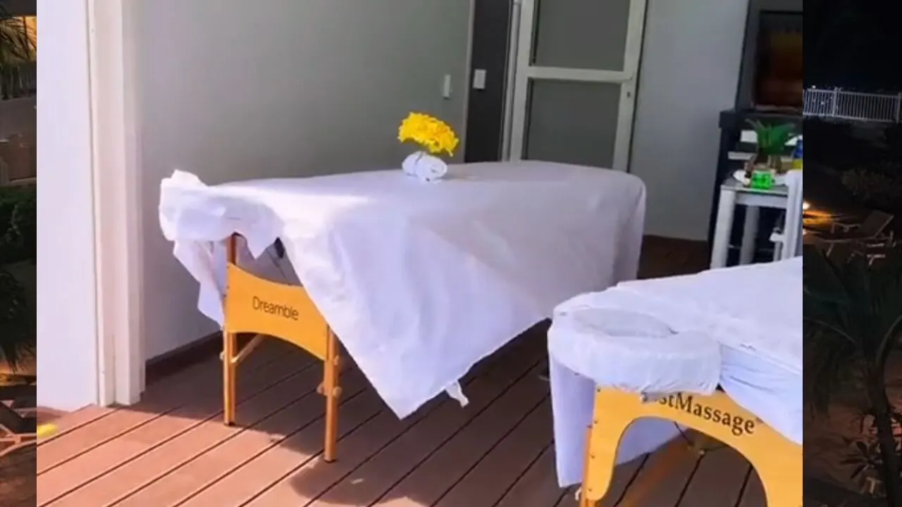 Two massage tables set up on a covered patio at dusk, one with a fresh yellow flower bouquet, ready for booking