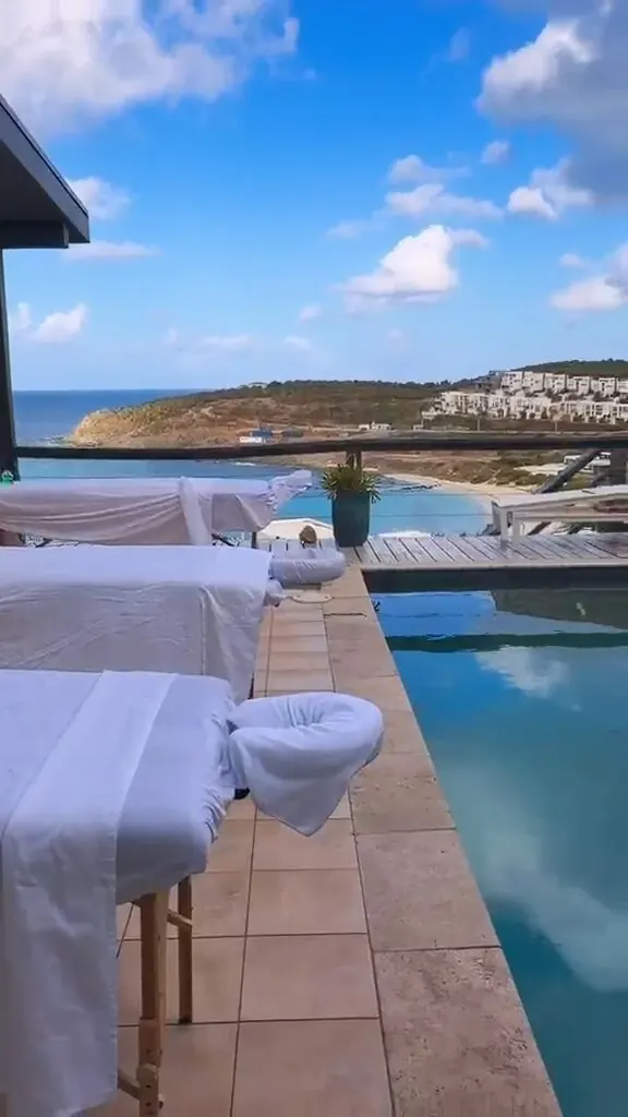 Massage tables set up poolside overlooking the ocean and coastal hillside