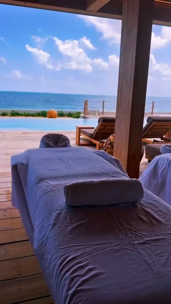 Massage table set up under a wooden pergola beside an infinity pool overlooking the ocean