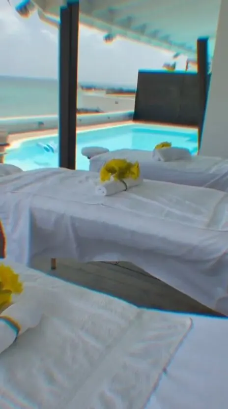 Guest relaxing during a massage on a covered terrace overlooking the ocean and an infinity pool