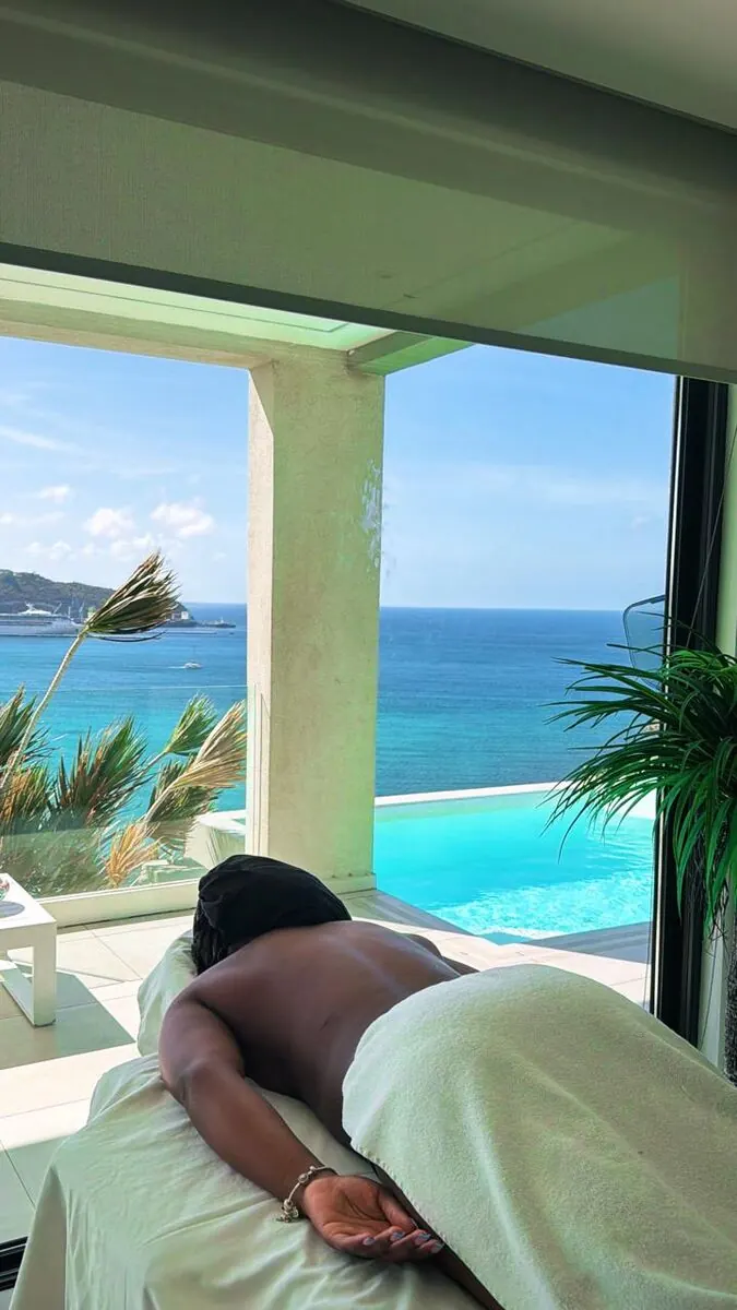 Guest receiving a massage on an oceanfront terrace with a cruise ship visible in the harbor below