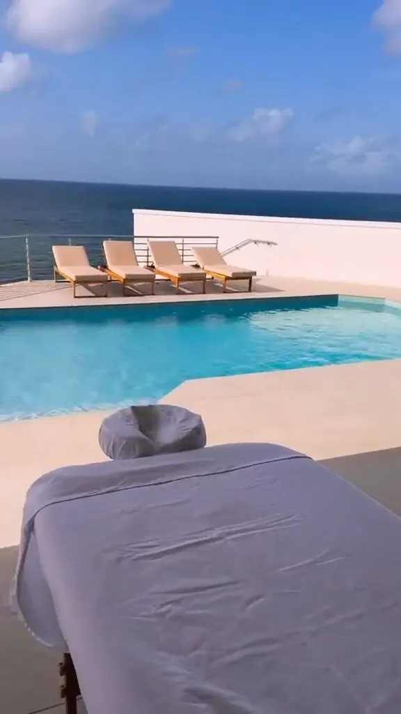 Massage table poolside overlooking an infinity pool and the open ocean, with lounge chairs nearby